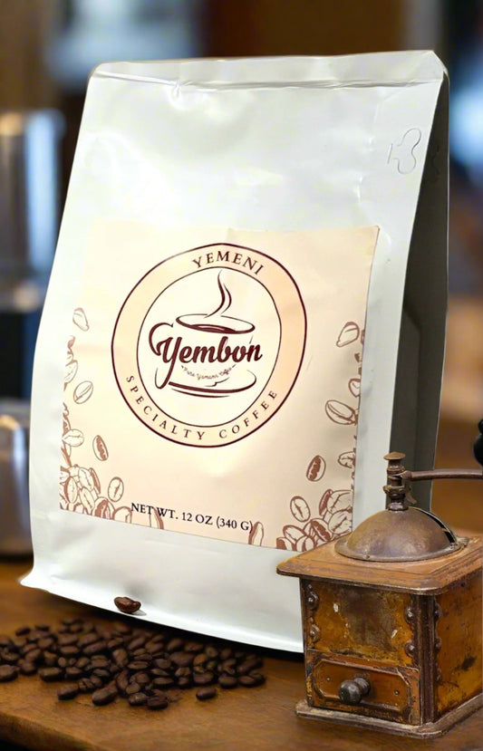 Yemeni Specialty Coffee bag with a vintage coffee grinder on a wooden surface.